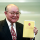Retired judge Woo Kwok-hing holds a copy of the Basic Law, the territory's mini constitution, as he announces his run in next year's chief executive election during a news conference in Hong Kong, Thursday, Oct. 27, 2016. (AP Photo/Kin Cheung)